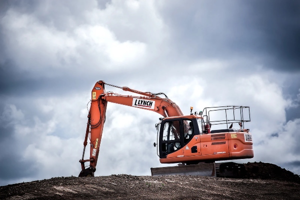 There is a heavy crane machinery on top of a pile of dirt digging ground for a new paved highway.