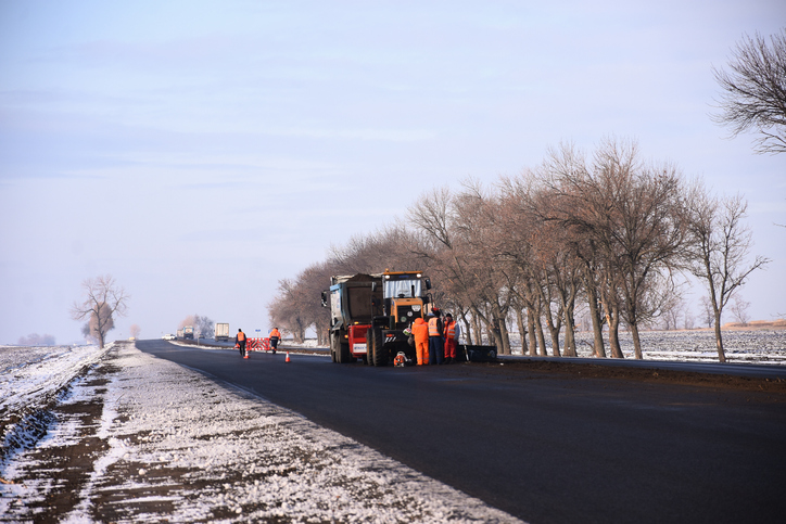 A municipal paving crew paves an asphalt county road. 