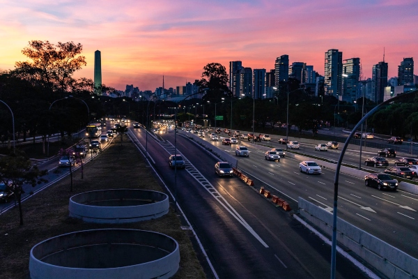 The sun rises over a city and over an asphalt-paved highway with stronger opportunities for paving in the future.