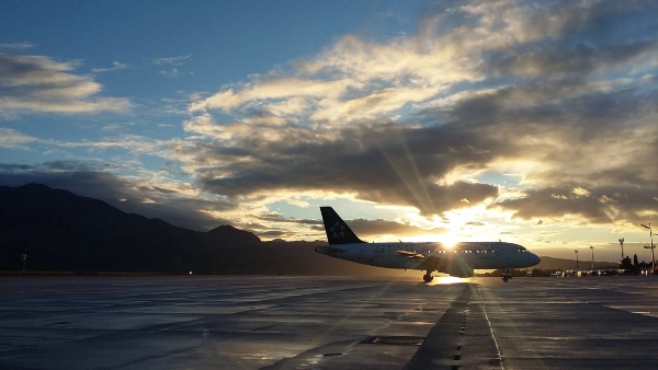 A plane is ready for takeoff as the sunrises over the freshly paved runway.